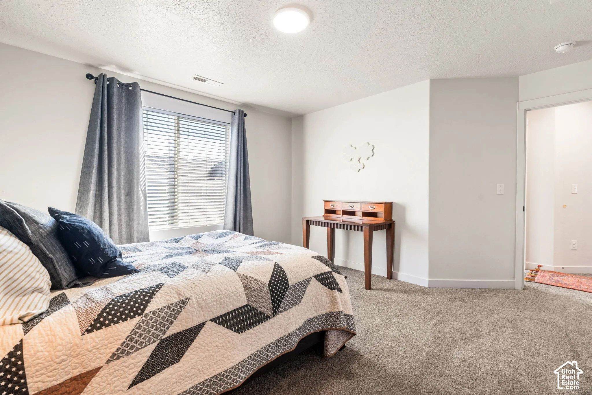 Neutral interior room featuring neutral wall paint, carpeted flooring, and a single window with horizontal blinds