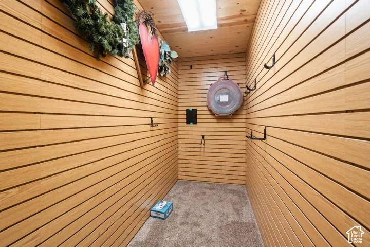 Plenty of storage! Wood-finish slat wall paneling, integrated wall-mounted hardware, wood-plank ceiling, and carpeted flooring