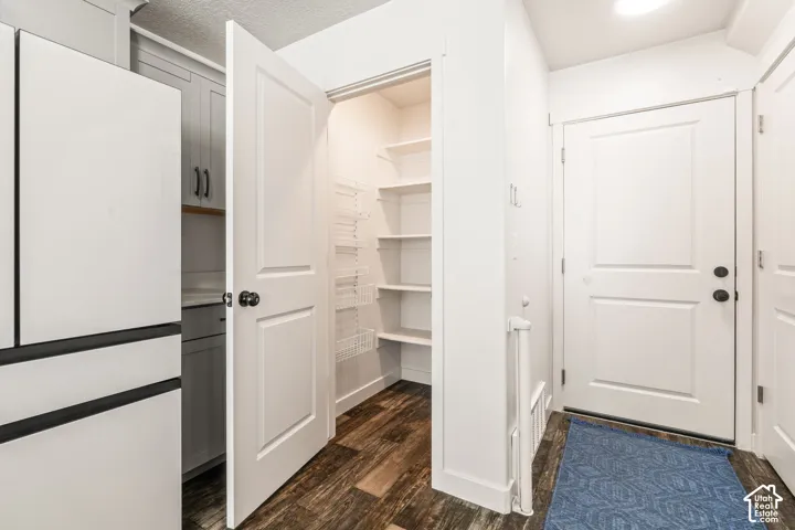 Pantry featuring multi-level shelving and interior door-mounted storage racks, wood-finish flooring, and shaker-style cabinetry with matte black hardware
