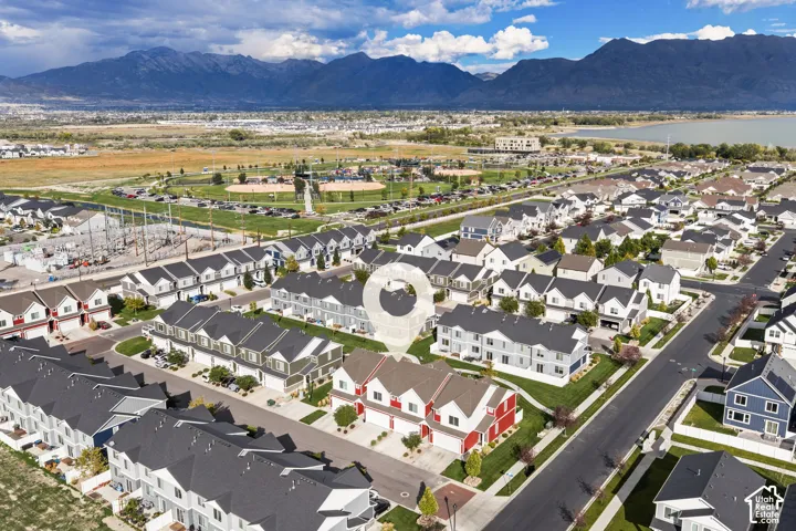 Aerial perspective of a multi-level residential structure featuring a two-car garage, steep gable rooflines, and a contrast-colored exterior facade, set against a prominent mountain range backdrop
