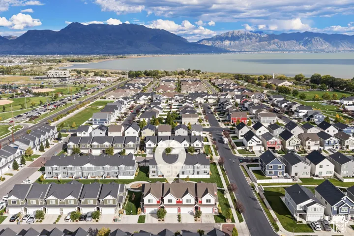 Aerial perspective of a multi-story residential building with a gabled roofline, concrete driveway, and mountain and lake scenery