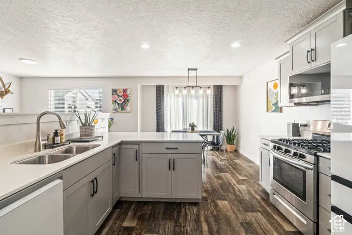 Kitchen featuring gray cabinetry, quartz countertops, stainless steel gas range, wood-finish flooring, and recessed lighting