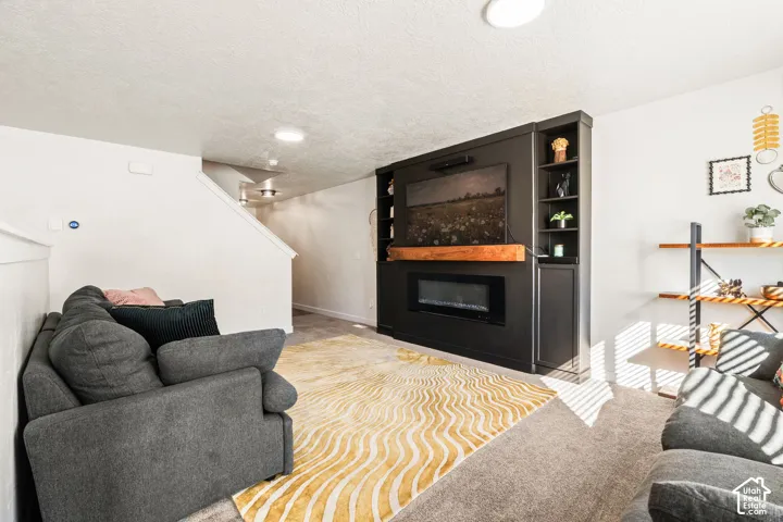Built-in wall unit featuring a custom matte black finish, integrated shelving, an electric fireplace, and a natural wood-finish mantel