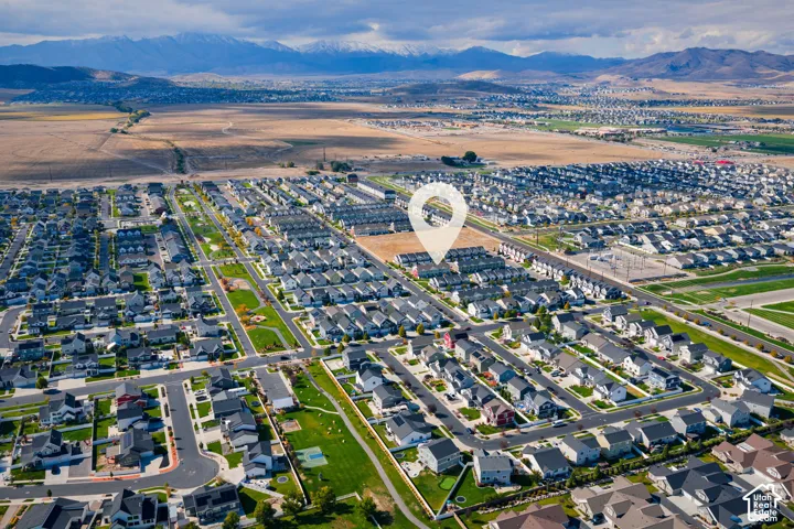 Aerial perspective of a residential community featuring a paved street network, integrated green spaces, and a mountainous backdrop