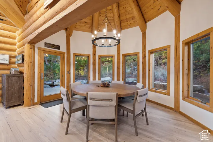 Dining space featuring a chandelier, light wood-type flooring, high vaulted ceiling, and a wooden ceiling with exposed beams