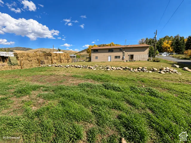 Expansive exterior grounds featuring a two-story residence, a stone retaining wall, and mountain terrain