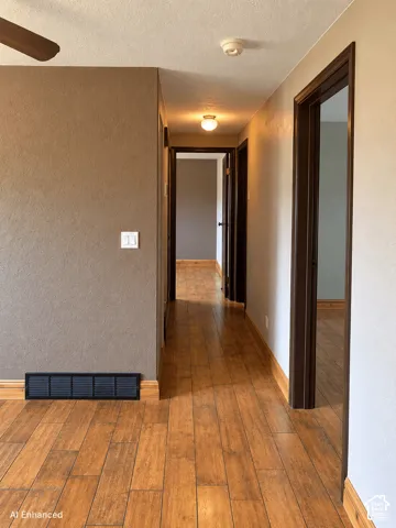 Interior hallway featuring wood-finish tile flooring, textured wall finishes, and dark wood-tone door casings