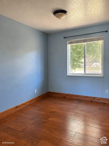 Room featuring wood-finish flooring, a sliding window with a horizontal rod, and a flush-mount ceiling fixture