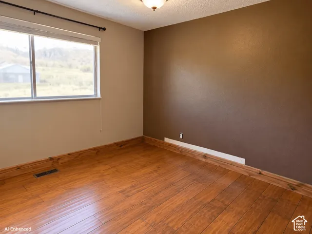 Interior room featuring wood-finish flooring, a dark accent wall, a sliding window with a curtain rod, and a flush-mount light fixture