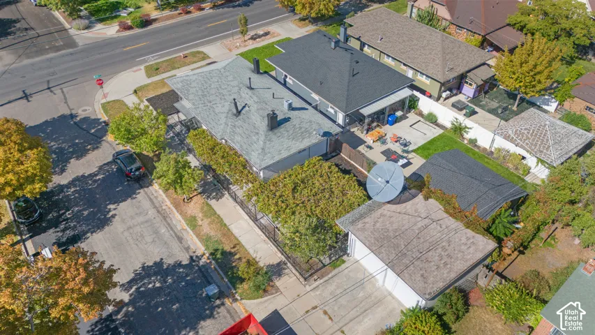 Aerial perspective of a property featuring a detached garage, concrete driveway, fenced yard, and shingle roofing