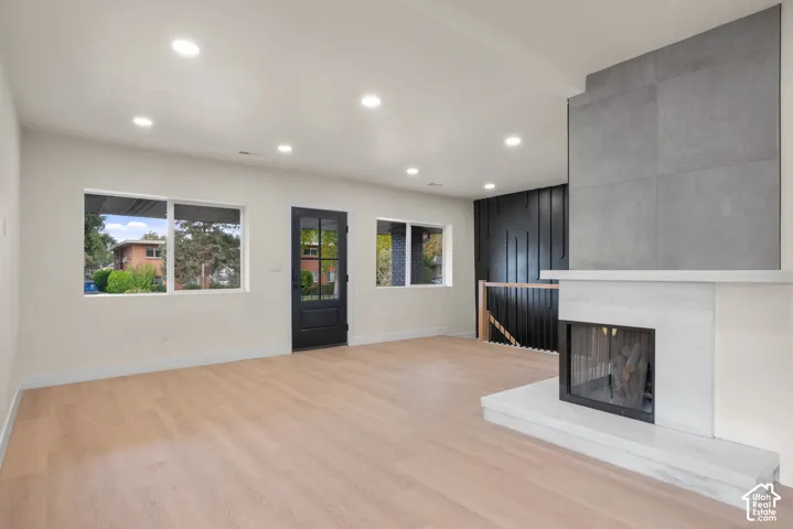 Living area featuring wood-finish flooring, recessed lighting, and a fireplace with a multi-textured surround