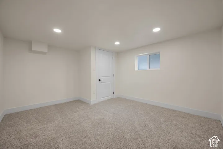 Neutral-toned interior space featuring recessed ceiling lighting, plush wall-to-wall carpeting, and a white paneled door with matte black hardware