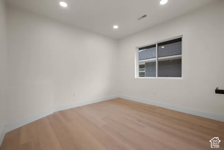 Room featuring light wood-finish flooring, neutral walls, recessed lighting, and a sliding window