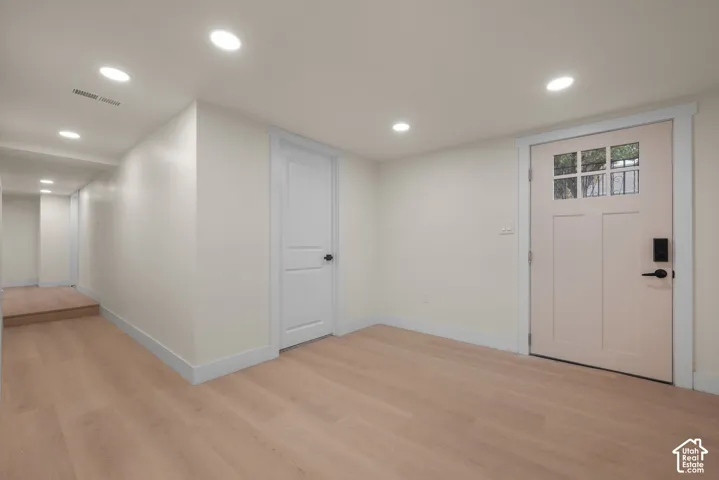 Interior entry featuring wood-finish flooring, recessed lighting, a multi-panel door with a glass inlay, and a matte black electronic deadbolt
