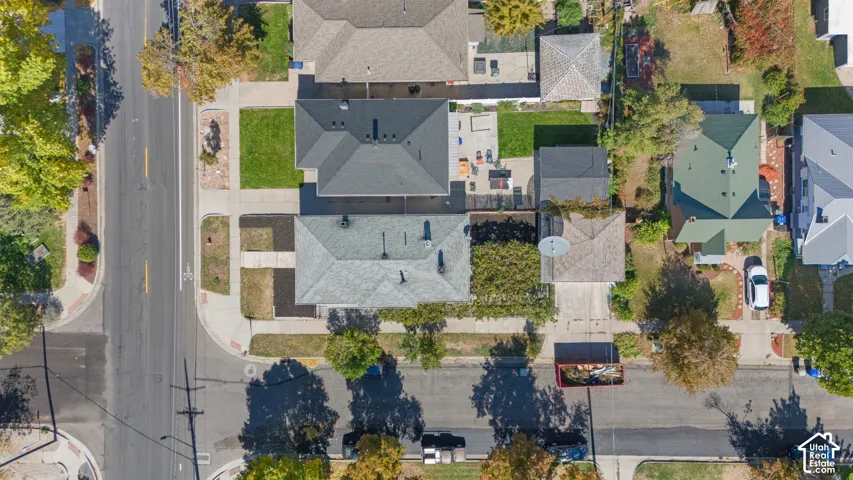 Corner lot property featuring a detached garage, rear concrete patio, and mature trees