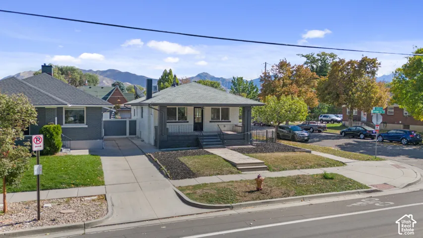 Single-story residence featuring a covered front porch with tapered columns, concrete driveway, and mountain backdrop