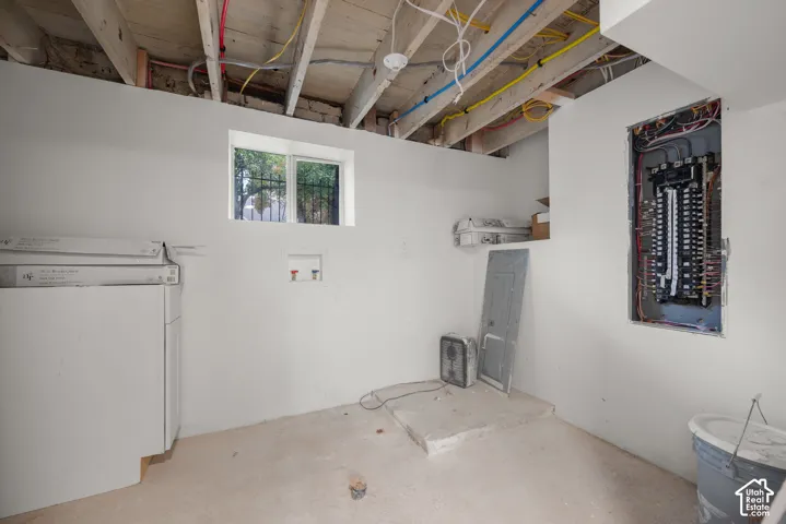 Utility area featuring a concrete floor, dedicated plumbing hookups, a recessed electrical panel, and a single-pane window