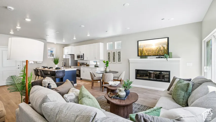 Open-concept interior featuring wood-finish flooring, recessed lighting, a modern linear fireplace, and kitchen cabinetry with a contrasting blue island