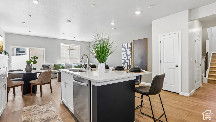Kitchen featuring a central island with a solid-surface countertop, stainless steel dishwasher, undermount sink, and recessed lighting throughout