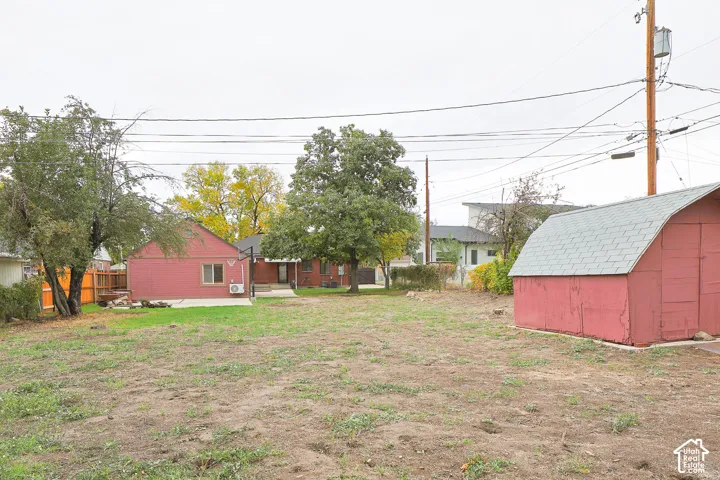 Expansive backyard featuring mature trees, a detached storage shed, and a concrete patio area