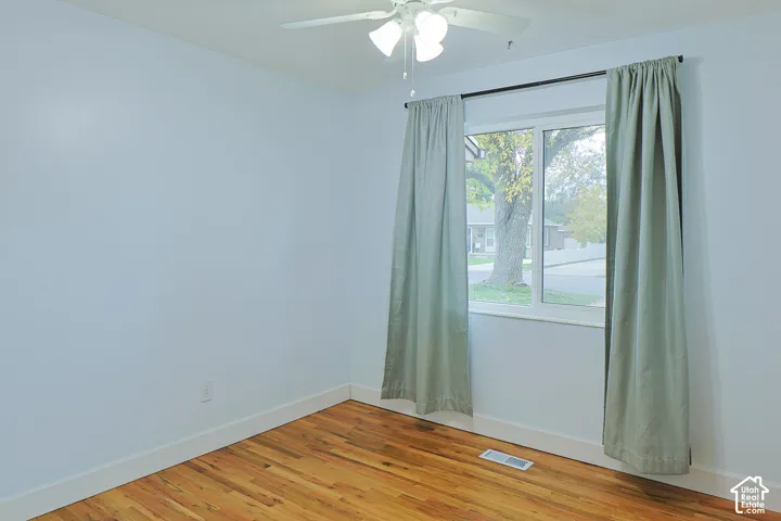 Wood-finish flooring and a white ceiling-mounted fan with integrated lighting