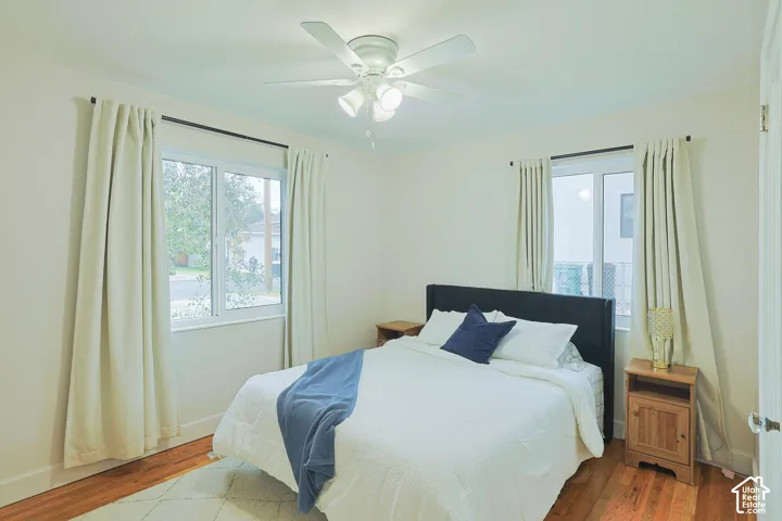Neutral wall palette, wood-finish flooring, dual sliding-sash windows, and a multi-blade ceiling fan with integrated lighting