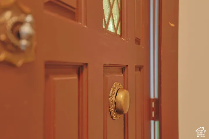 Six-panel wood door featuring a diamond-patterned glass inset, decorative metal door knocker, and an ornate brass finish entry hardware set