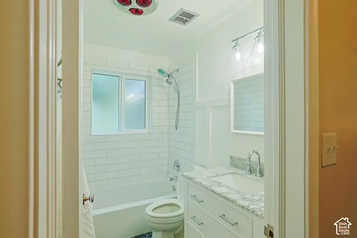 Bathroom featuring a white vanity with a stone countertop, an integrated rectangular sink, subway tile shower surround, and a wall-mounted mirror