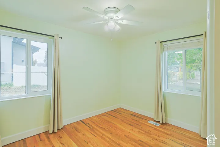 Wood-finish flooring, white-framed dual-pane sliding windows, and a ceiling fan with integrated lighting