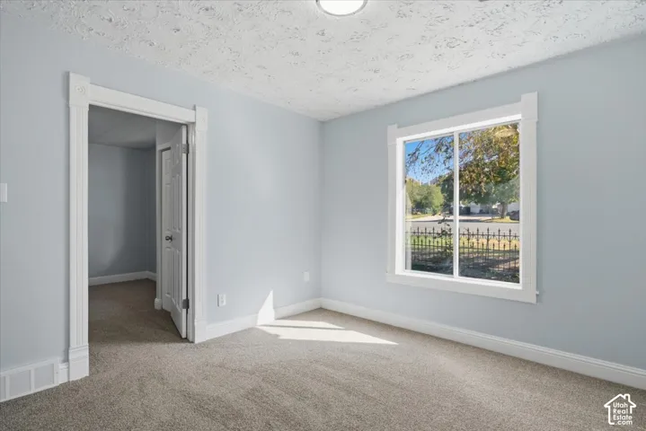 Room featuring neutral wall tones, neutral carpeting, white trim, a sliding window with exterior scenery, and a doorway with a panel door
