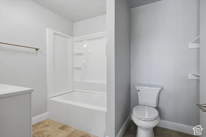 Full bathroom featuring a tub-shower combination with integrated shelving, white vanity, ceramic tile flooring, and built-in wall shelving