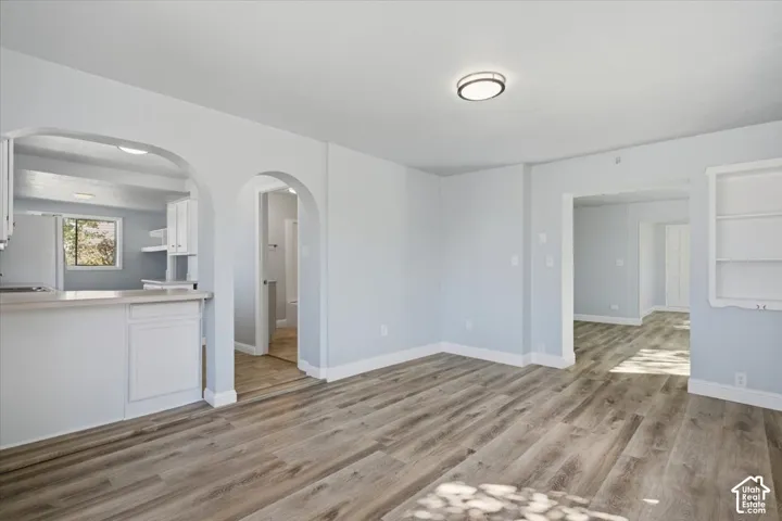 Interior space featuring wood-finish flooring, architectural archways, built-in shelving, and a breakfast bar