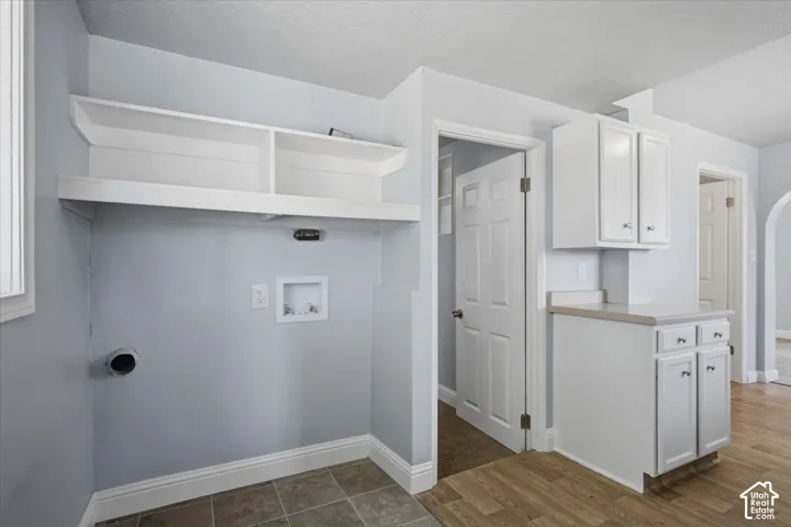 Utility area featuring white built-in upper cabinetry, open shelving, stone-finish countertops, tile flooring, and a six-panel door