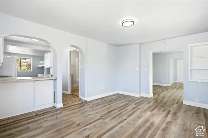 Open-concept interior featuring archway architectural details, wood-finish flooring, a built-in wall niche, and a peninsula counter