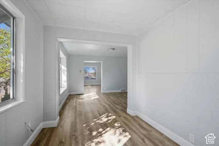 Interior space featuring wood-finish flooring, white painted brick-texture walls, a tiled ceiling, and large windows