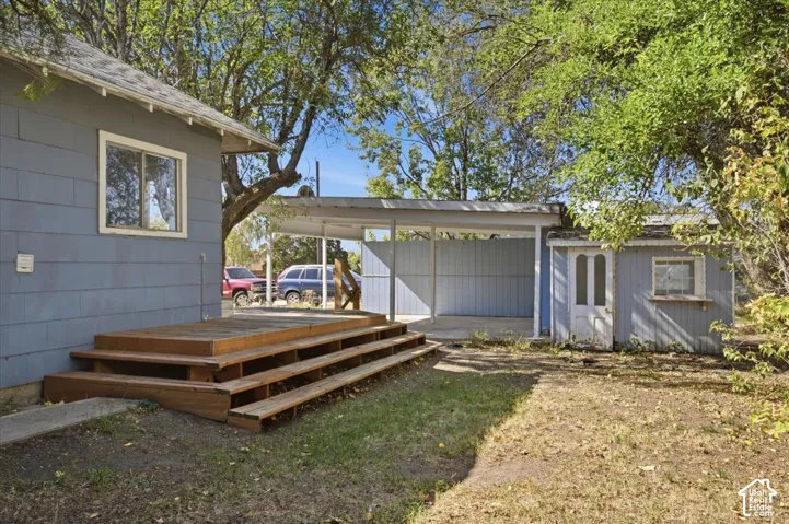 Exterior area featuring a multi-tiered wood deck, a covered carport, and a detached outbuilding