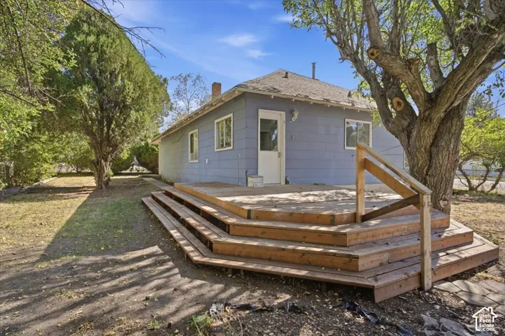 Multi-tiered wood deck featuring a built-in handrail, siding exterior, and mature trees