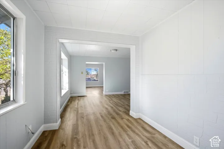 Wood-finish flooring, white painted brick walls, tile-patterned ceiling panels, and ample window light