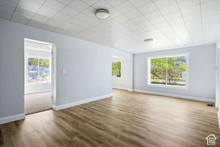 Interior space featuring wood-finish flooring, large windows, and a grid-patterned drop ceiling with flush-mount lighting fixtures