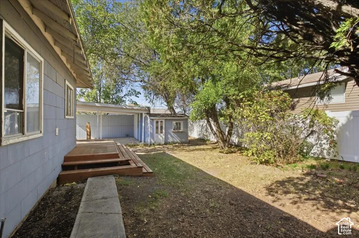 Backyard area featuring a wood deck, detached storage structure, concrete walkway, and privacy fencing