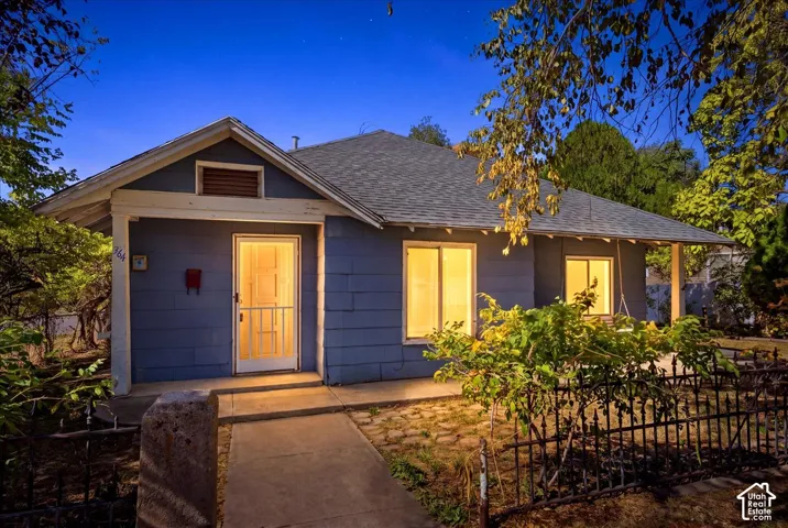 Single-story residence featuring a blue shingle exterior, covered front porch, gabled roofline, and metal fencing