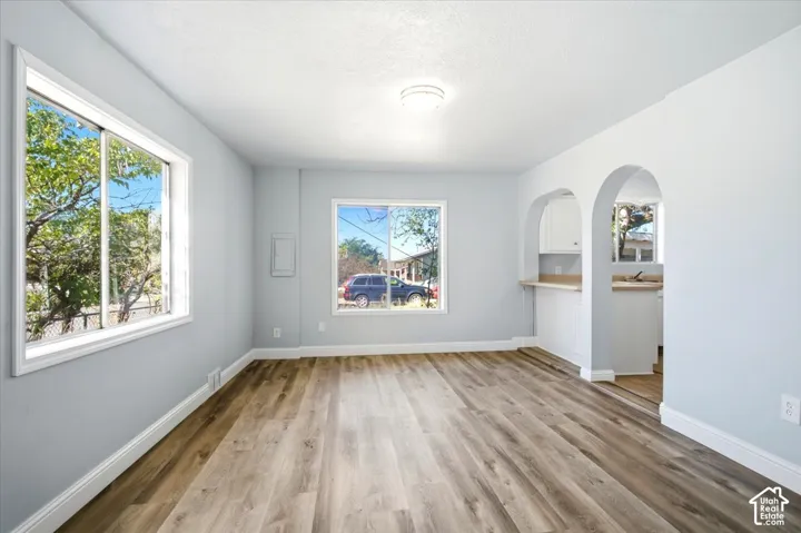 Interior space featuring wood-finish flooring, two large windows, and a dual-archway opening