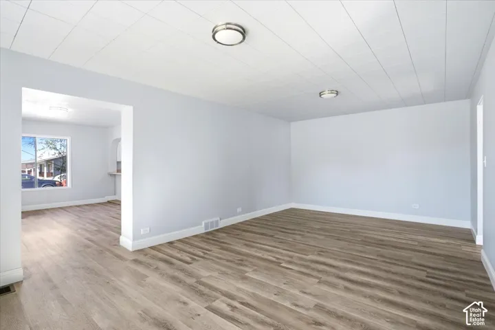 Interior space featuring neutral wall paint, wood-finish flooring, tile ceiling panels, and circular flush-mount lighting fixtures
