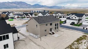 Two-story residence featuring a neutral-tone exterior, asphalt shingle roof, multi-pane windows, white perimeter fencing, and mountain scenery