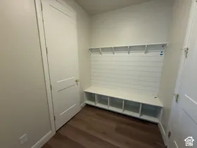 Built-in wall-to-wall bench with cubby storage, horizontal shiplap wall paneling, and an integrated upper shelf, complemented by wood-finish flooring and solid-core paneled doors