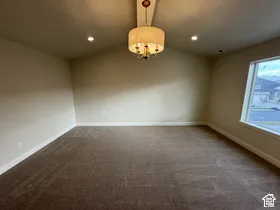 Vaulted ceiling featuring a central drum chandelier, recessed lighting, and large windows