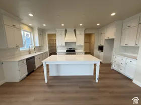 Kitchen featuring white cabinetry, a center island with a quartz countertop, stainless steel appliances, recessed lighting, and wood-finish flooring