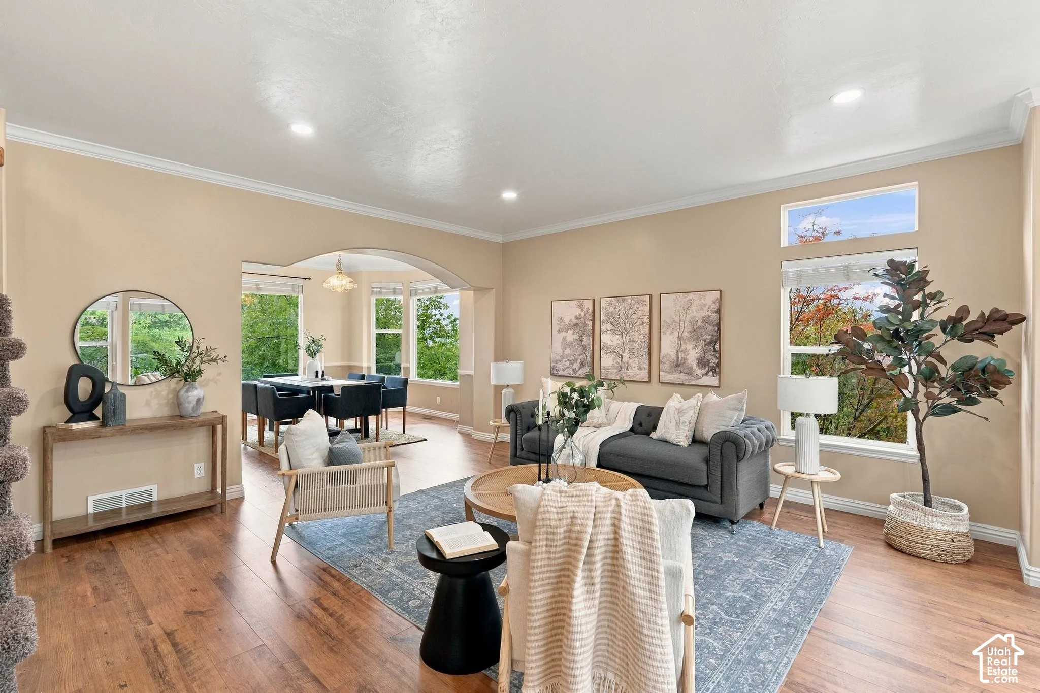 Open-concept interior featuring wood-finish flooring, recessed lighting, crown molding, and a prominent arched entryway