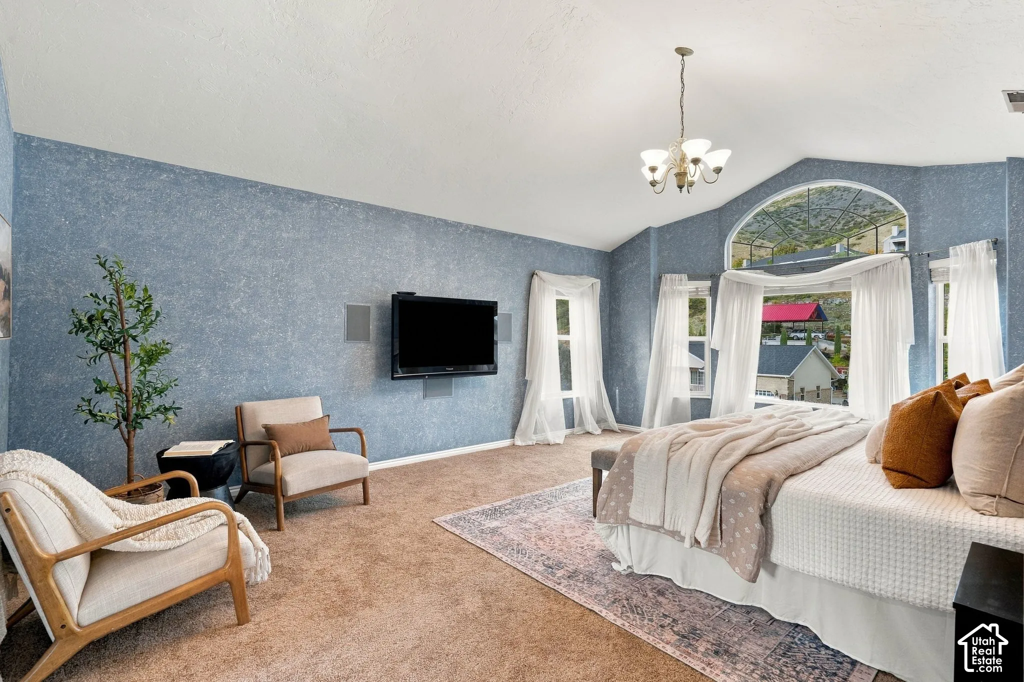Vaulted ceilings, arched windows, and multi-light chandelier featuring a textured blue wall finish