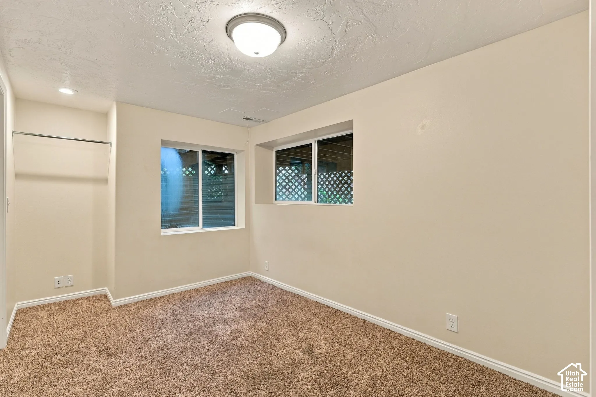 Room featuring wall-to-wall carpeting, dual sliding windows, and a built-in closet rod